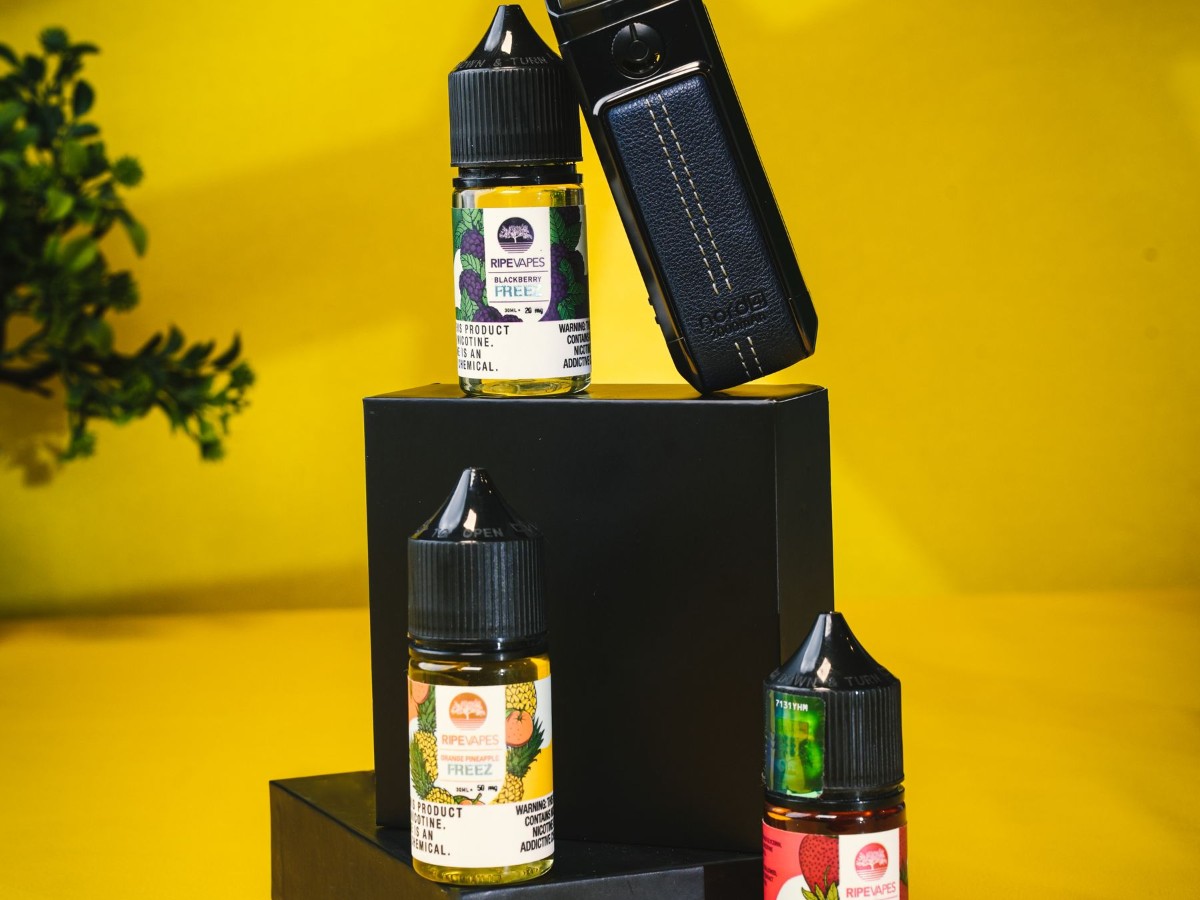 E-liquid bottles and a vape device arranged on a surface