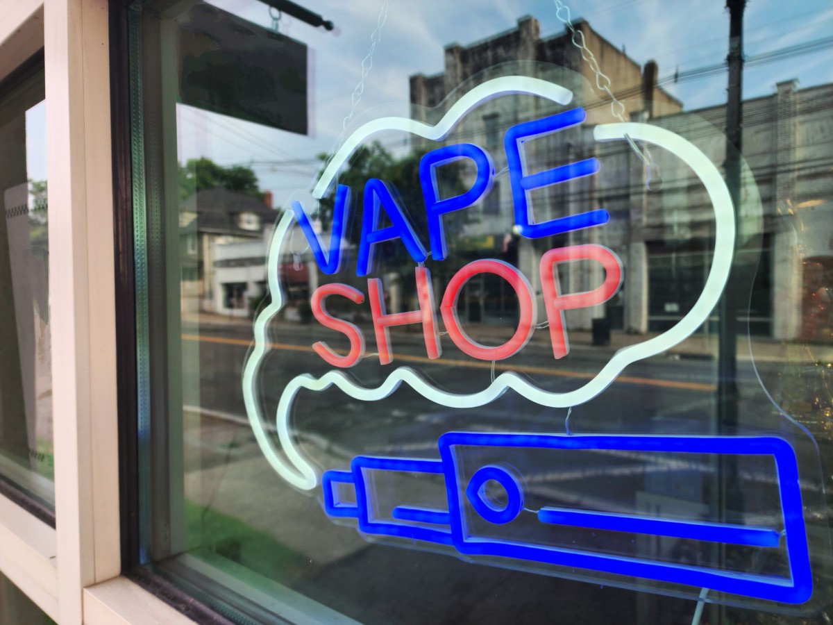 Neon vape shop sign in a storefront window Neon vape shop sign in a storefront window